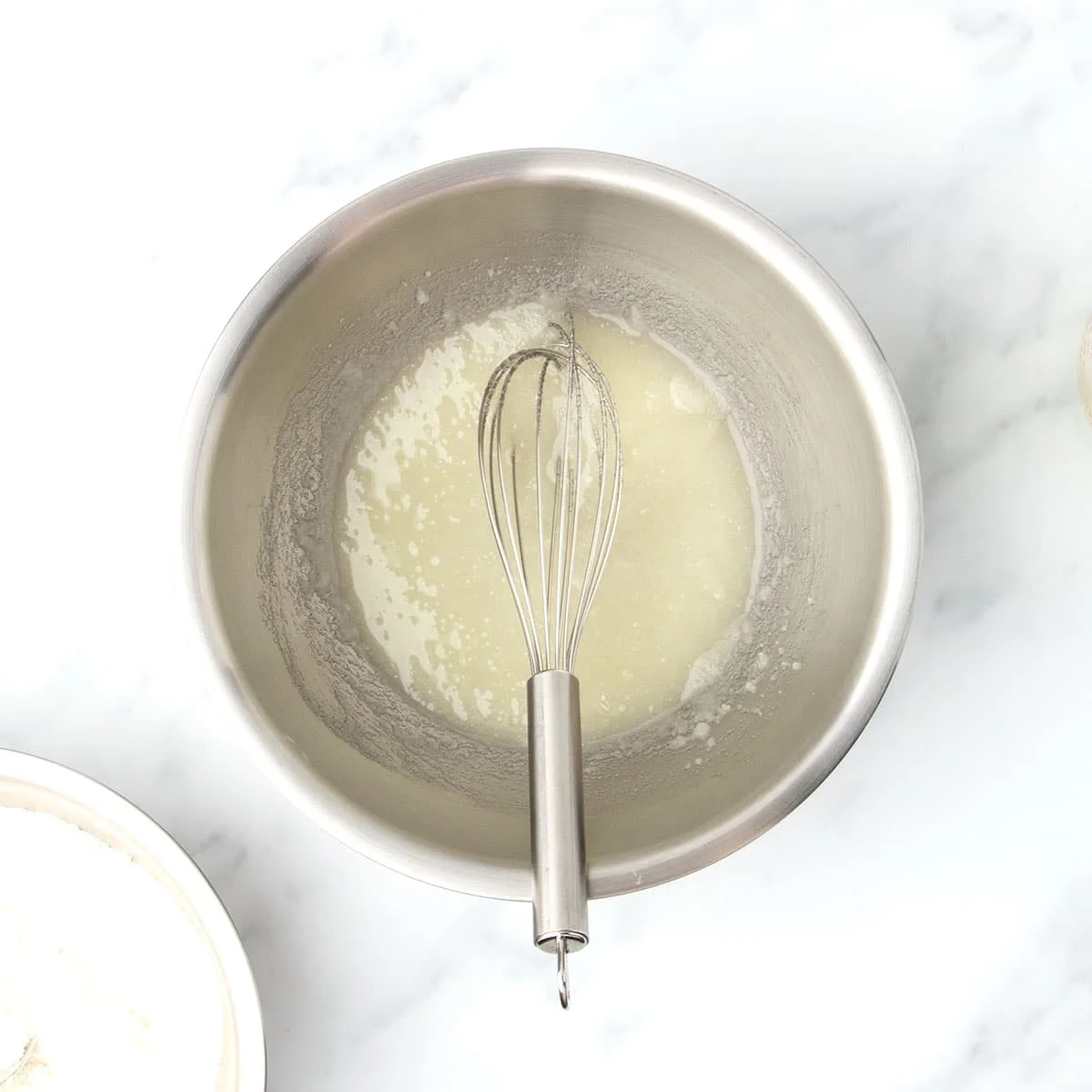 Granulated sugar and neutral oil whisked together in a large stainless steel mixing bowl until well combined and the sugar is dissolved.