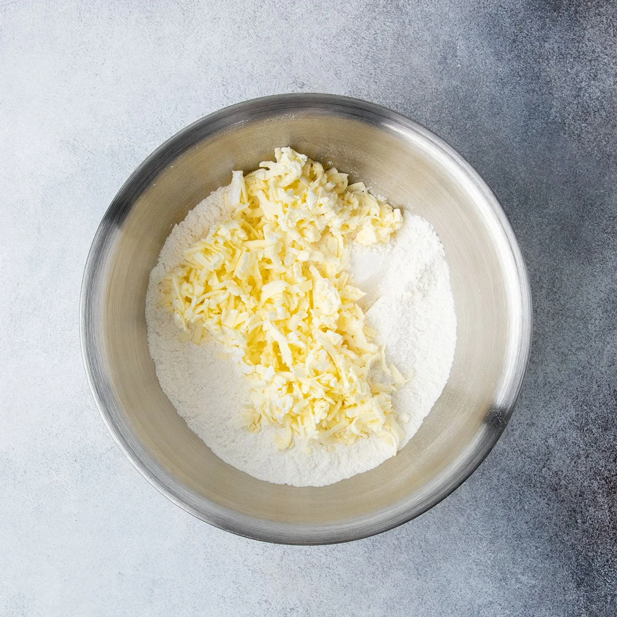 Grated butter added to a bowl of gluten free flour in the first step of making the cobbler topping.