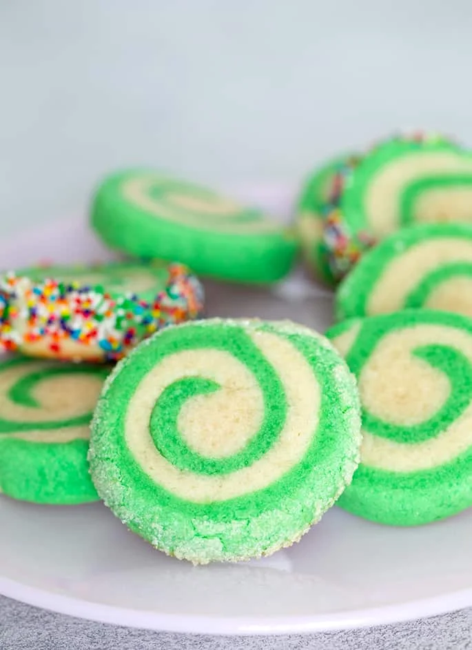 Green and white pinwheel cookies on a small plate.
