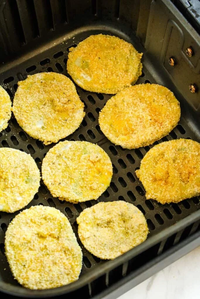 Green tomatoes in the air fryer about to be air fried.