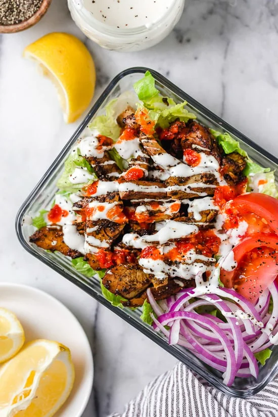 Halal Food Cart inspired chicken served over a big salad of lettuce and tomatoes drizzled with a yummy white sauce.