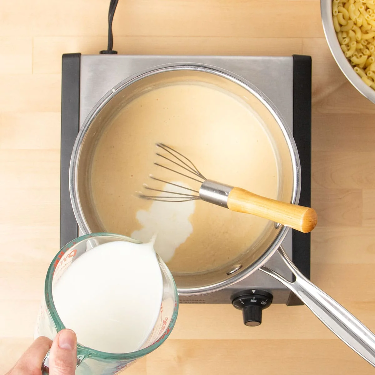 Hand pouring milk from glass measuring cup.