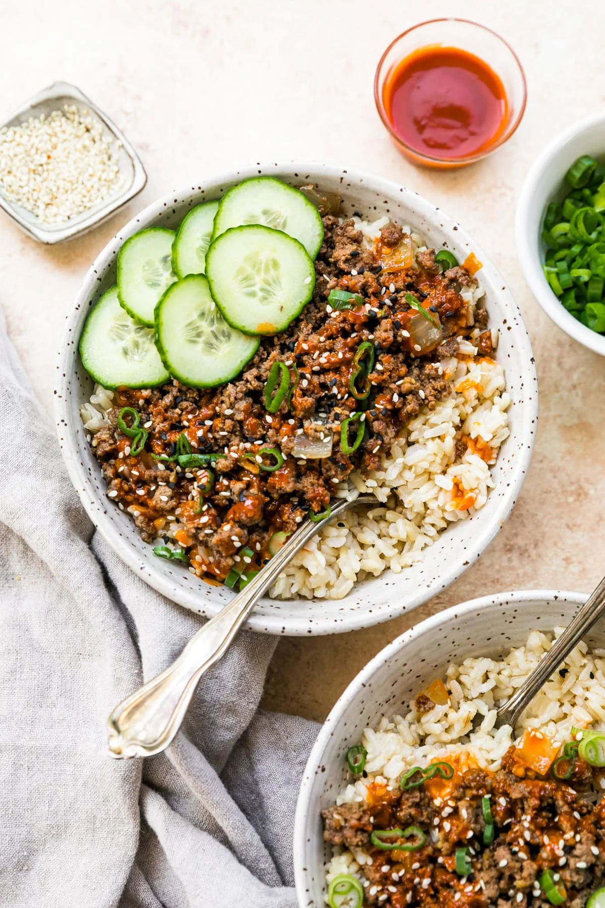 Homemade Korean beef served in a white bowl with rice and cucumber slices.