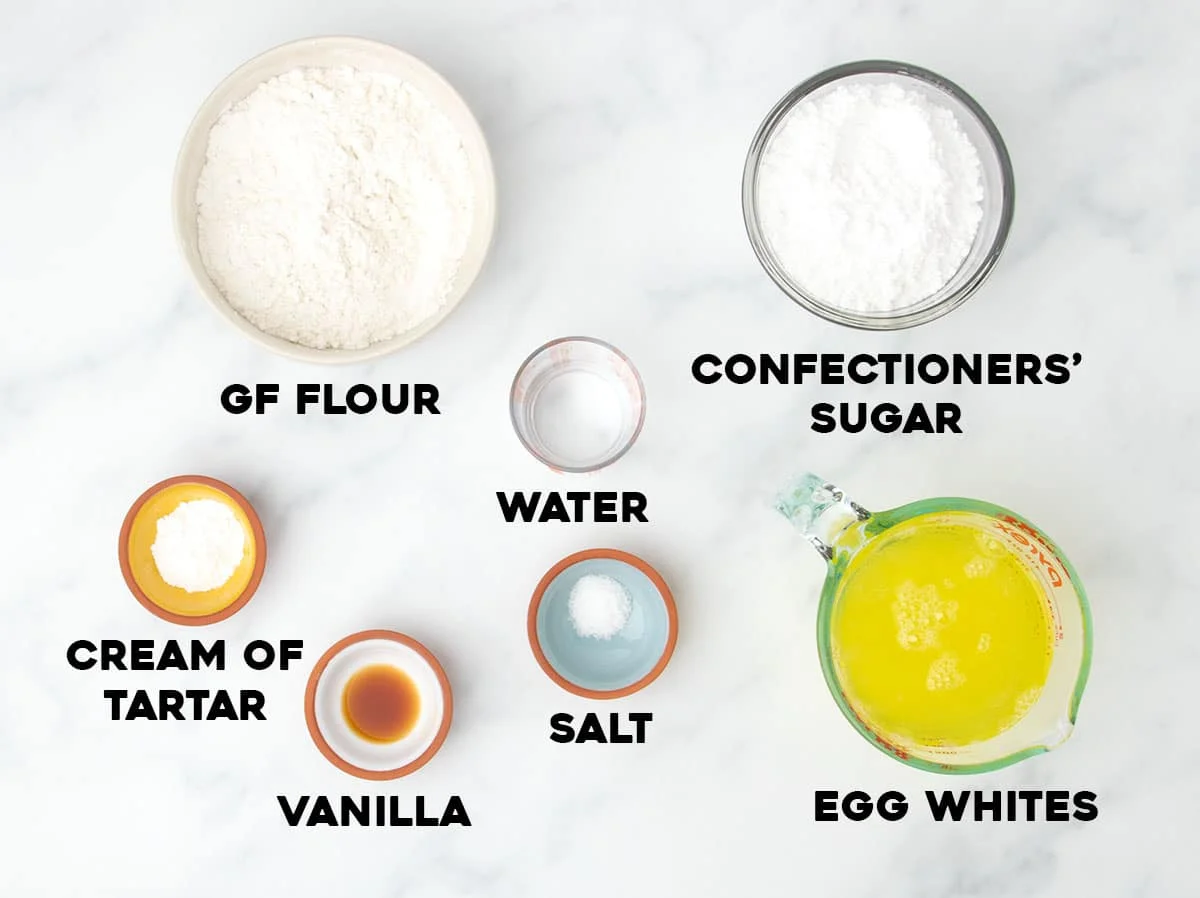 ingredients for gluten free angel food cake in small bowls with black block letters spelling name of each ingredient