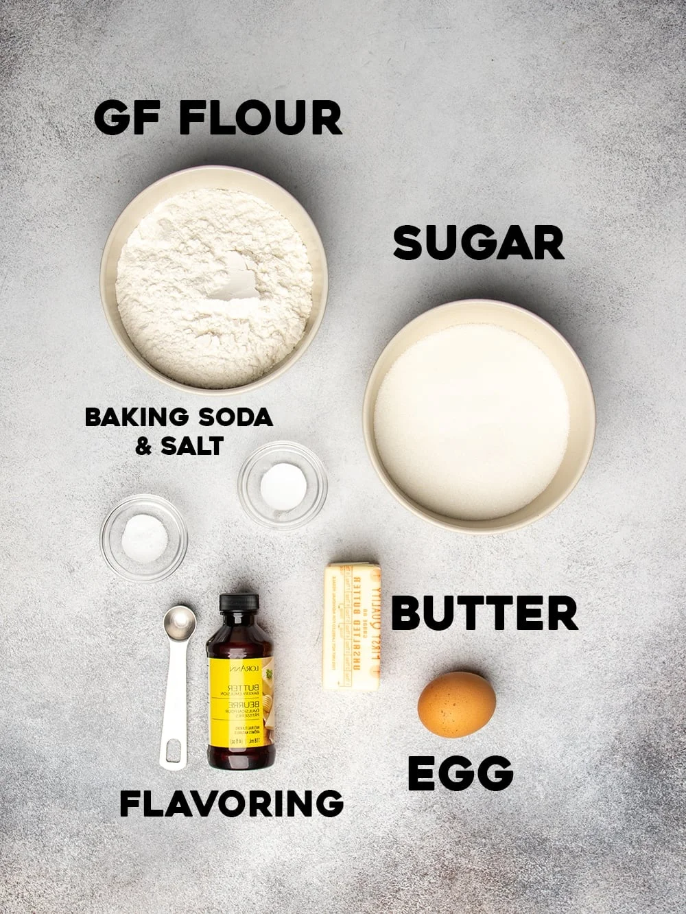 Ingredients for gluten free Crumbl cookies seen from overhead in small bowls with words, gf flour, sugar, baking soda & salt, butter, egg, and flavoring