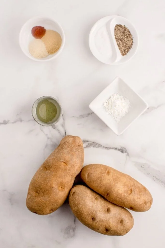 Ingredients needed to make air fryer french fries: russet potatoes, oil, garlic powder, onion powder, smoked paprika, salt, pepper, and cornstarch.