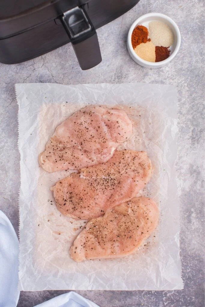 Ingredients needed to make air fryer grilled chicken: boneless chicken breasts, garlic powder, onion piwder, paprika, cayenne pepper, salt, and pepper. 