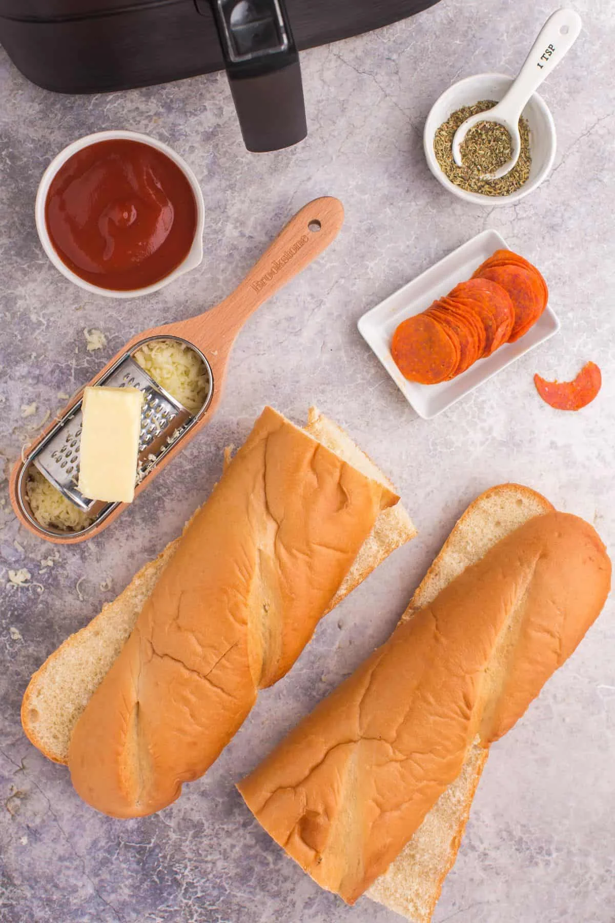 Ingredients needed to  make french bread pizza in the air fryer: french bread loaf, marinara, mozzarella cheese, italian seasoning, and pepperoni.