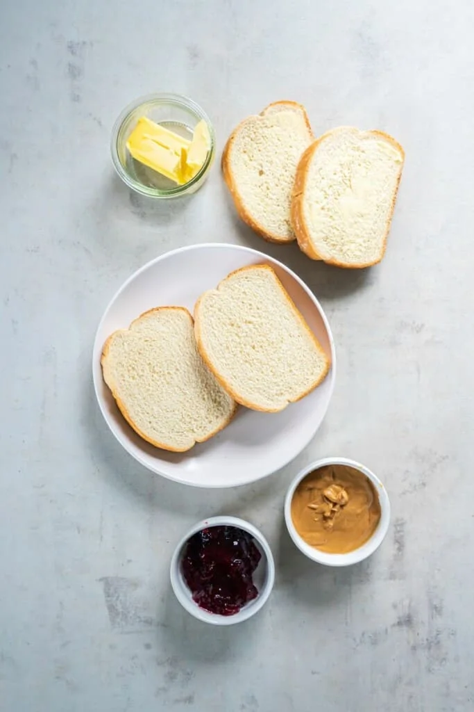 Ingredients needed to prepare peanut butter and jelly sandwiches in the air fryer.