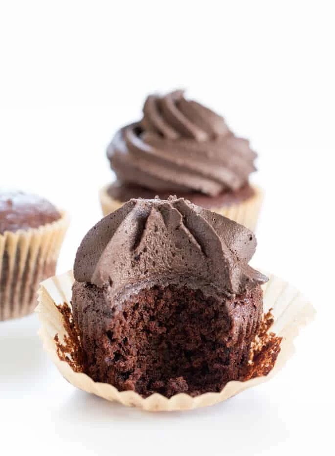 Inside of chocolate cupcakes with 2 other chocolate cupcakes in back on white surface 
