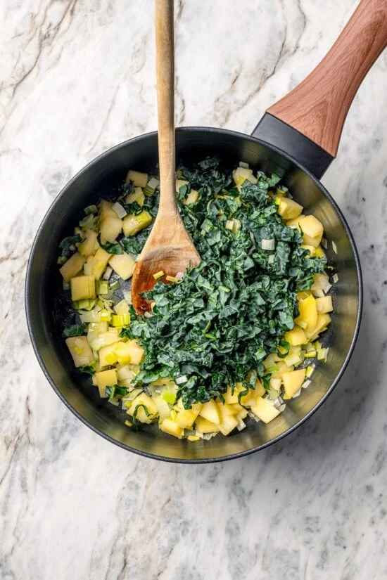 Kale added to pan of leeks and apples.