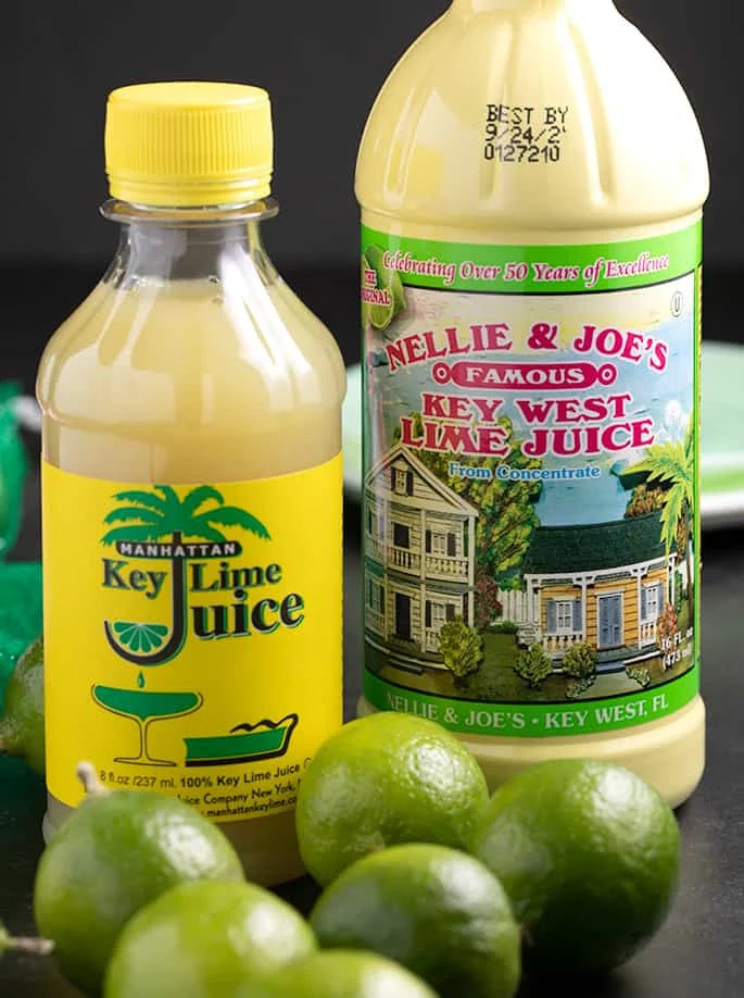 Key limes on table with two brands of bottled key lime juice