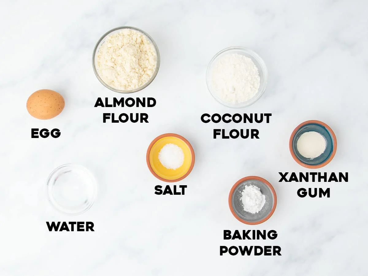 Labeled ingredients for almond flour tortillas arranged on a white marble surface.