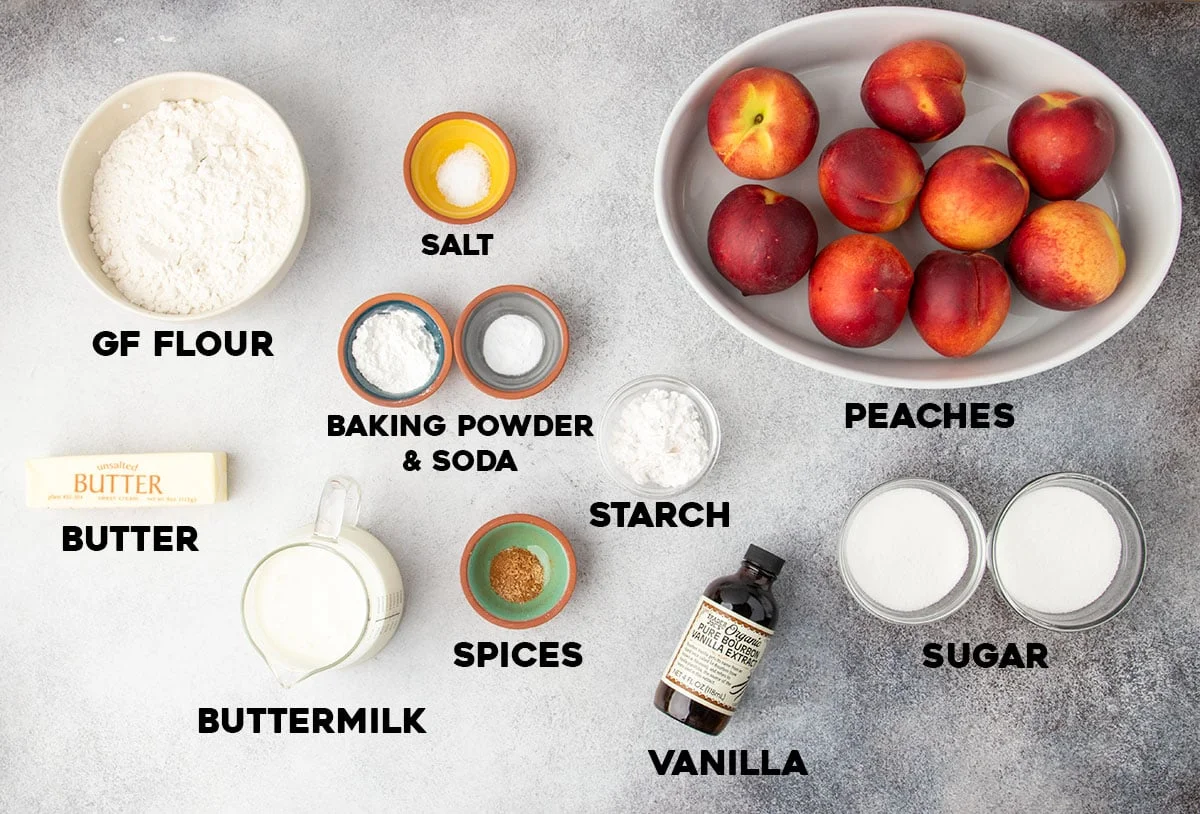 Labeled ingredients laid out for making the cobbler, including gluten free flour, sugar, butter, fresh peaches, and vanilla.