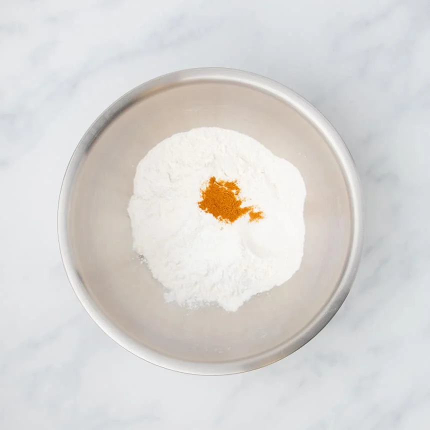 large round metal mixing bowl with white powder with the orange-brown color of paprika on top