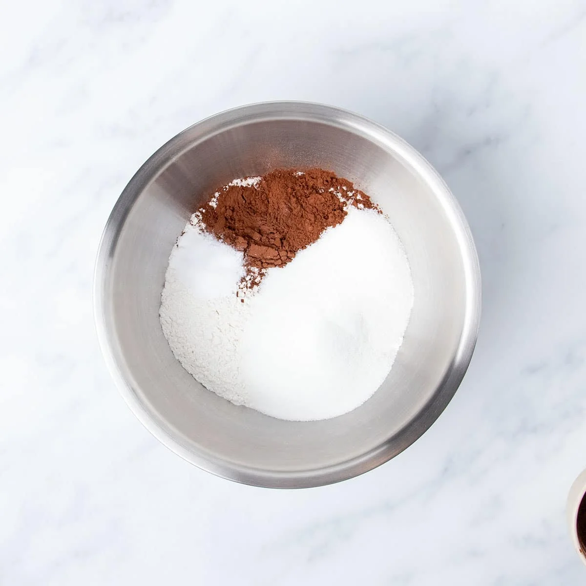 large round metal mixing bowl with white powders and some brown cocoa powder