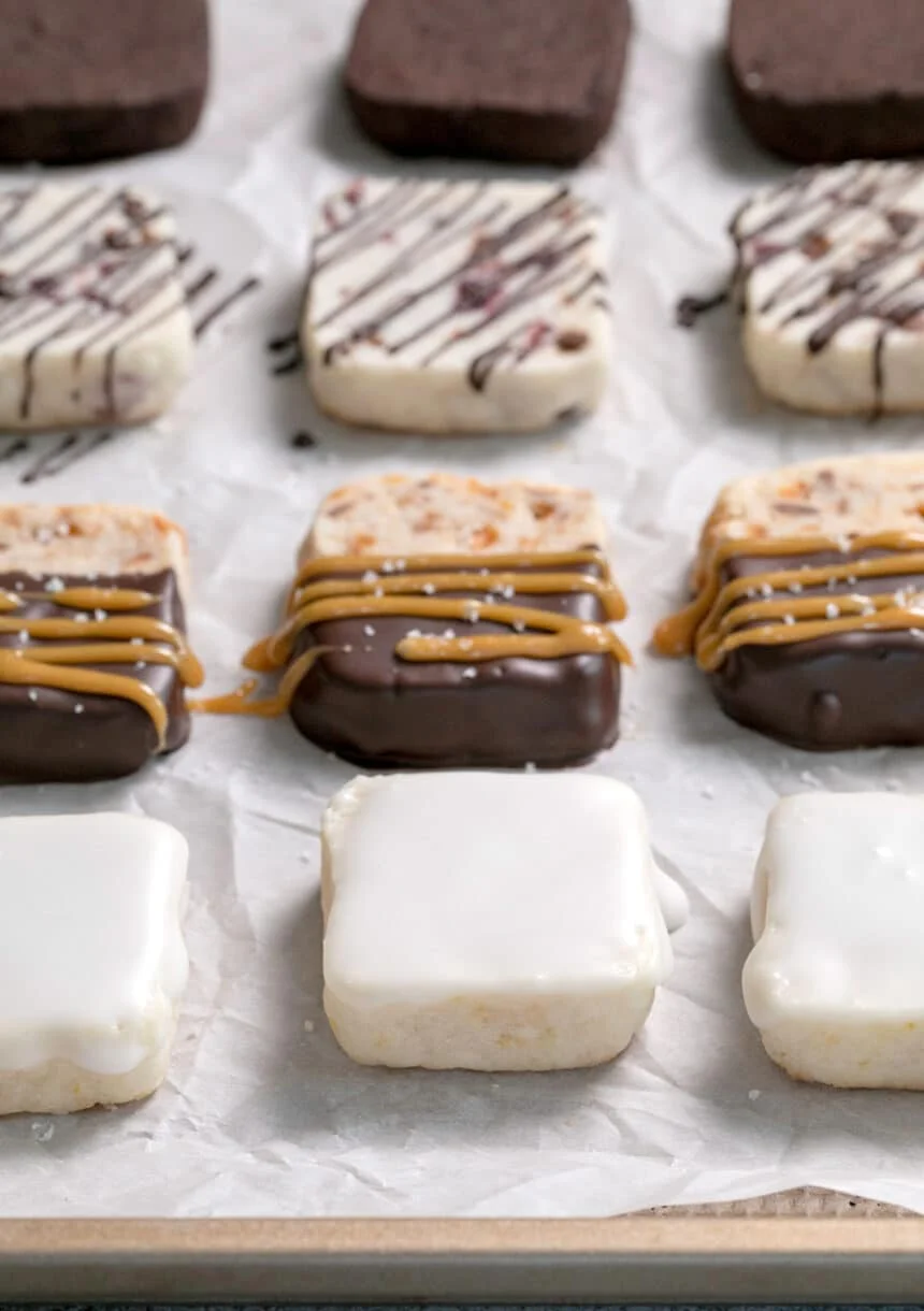 Lemon-glazed-toffee-caramel-berry-chip-and-mocha-shortbread-cookies-on-white-paper-on-a-tray