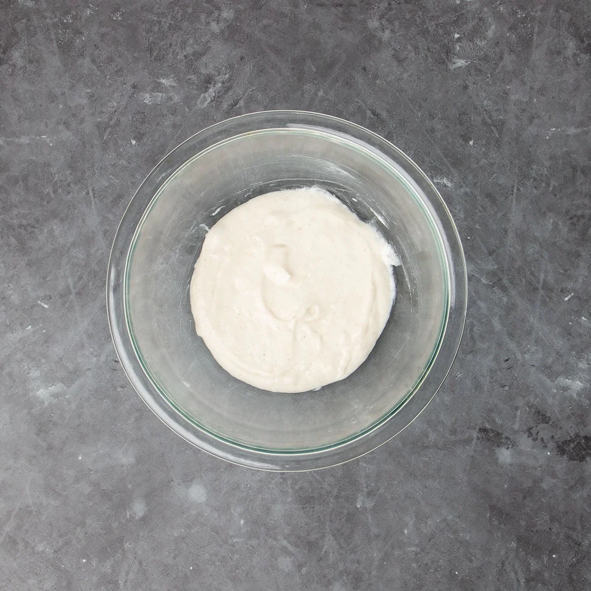 light tan shapeless unrisen dough starter in small glass bowl