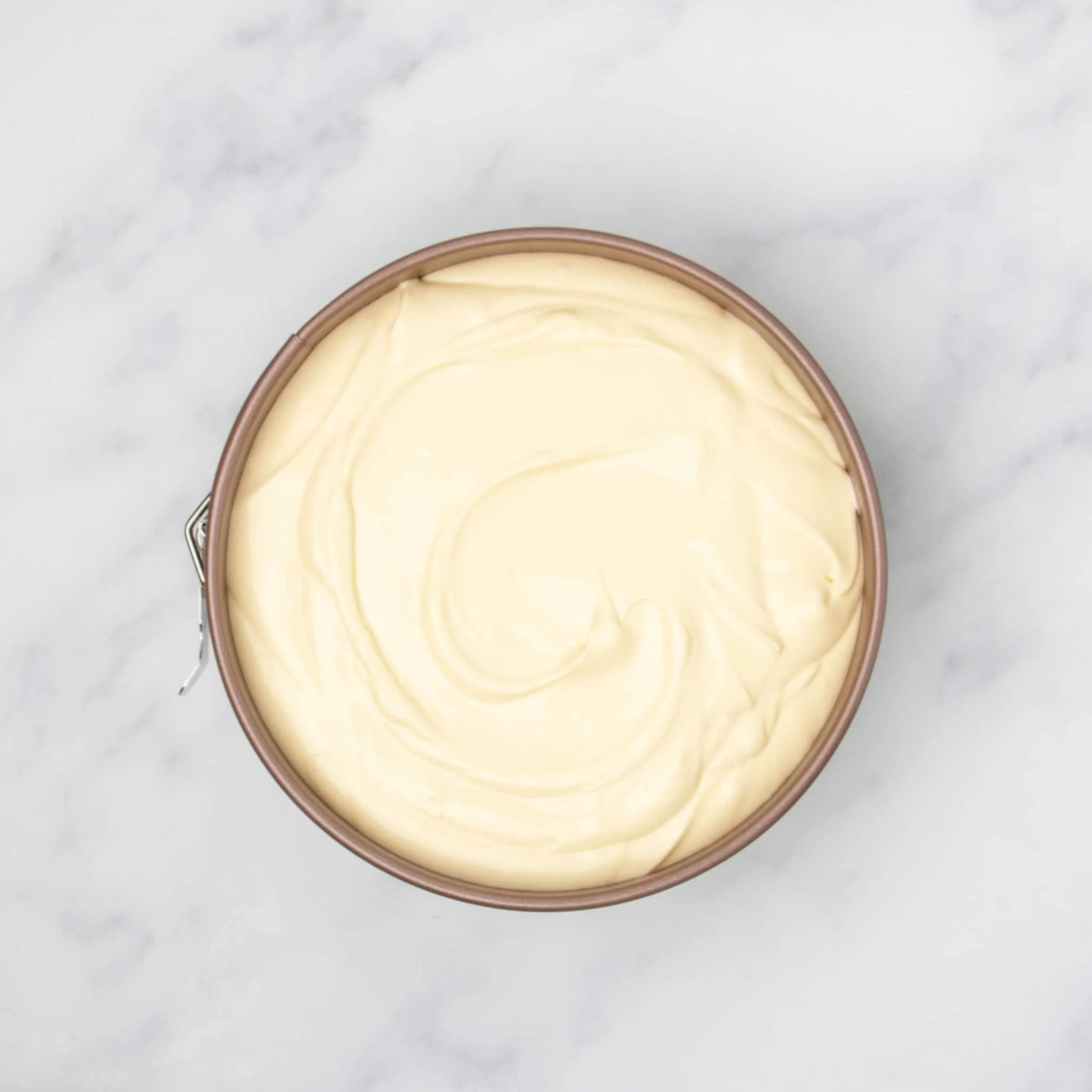 light yellow raw cheesecake mixture in gold colored round springform pan