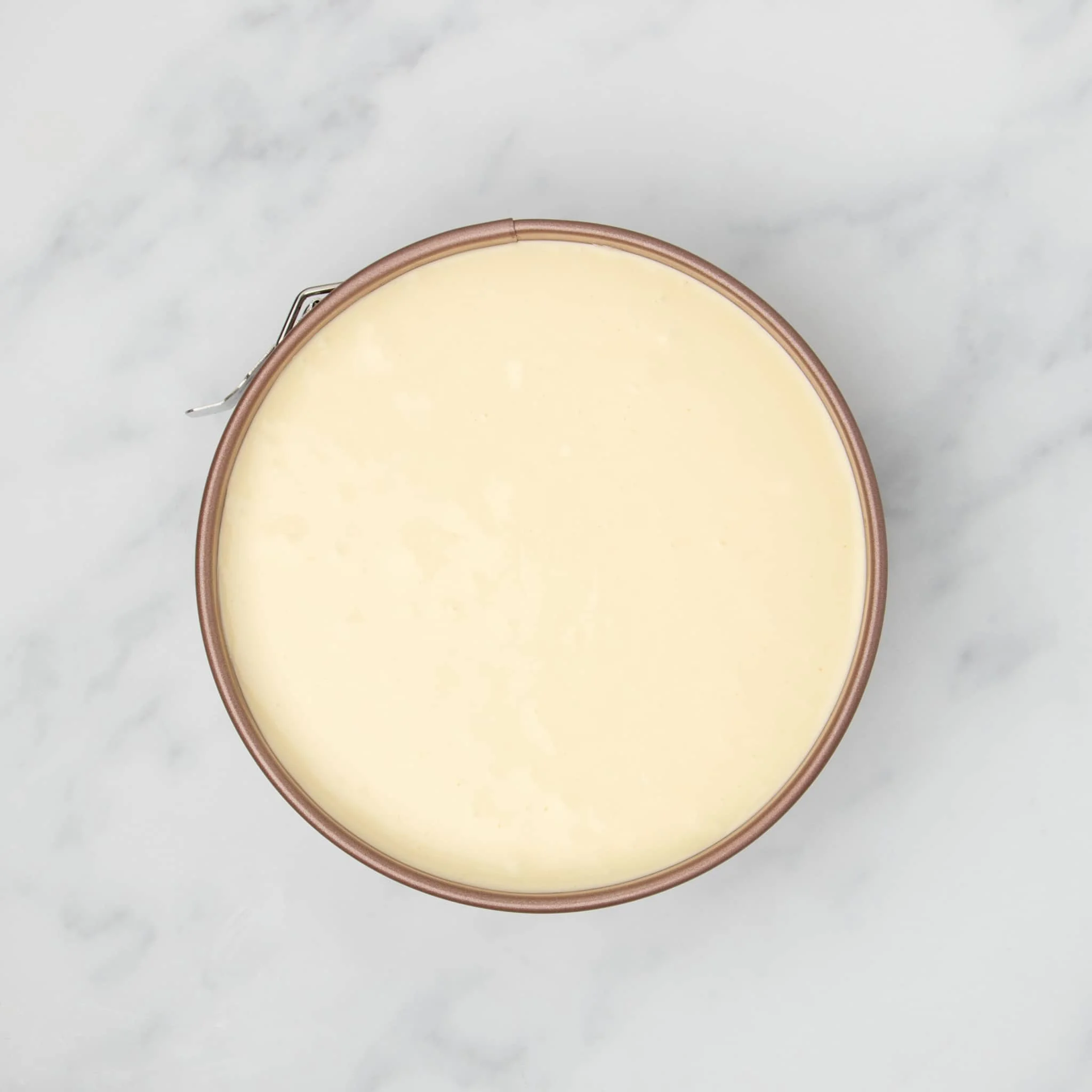 light yellow raw cheesecake mixture in same pan smoothed out into even layer