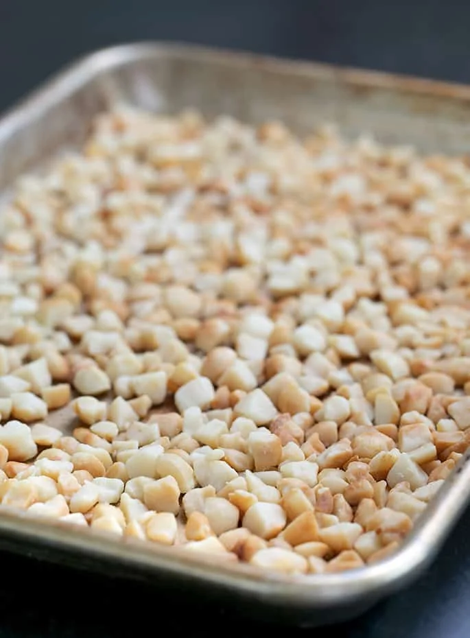 Macadamia nut pieces toasted on a tray.