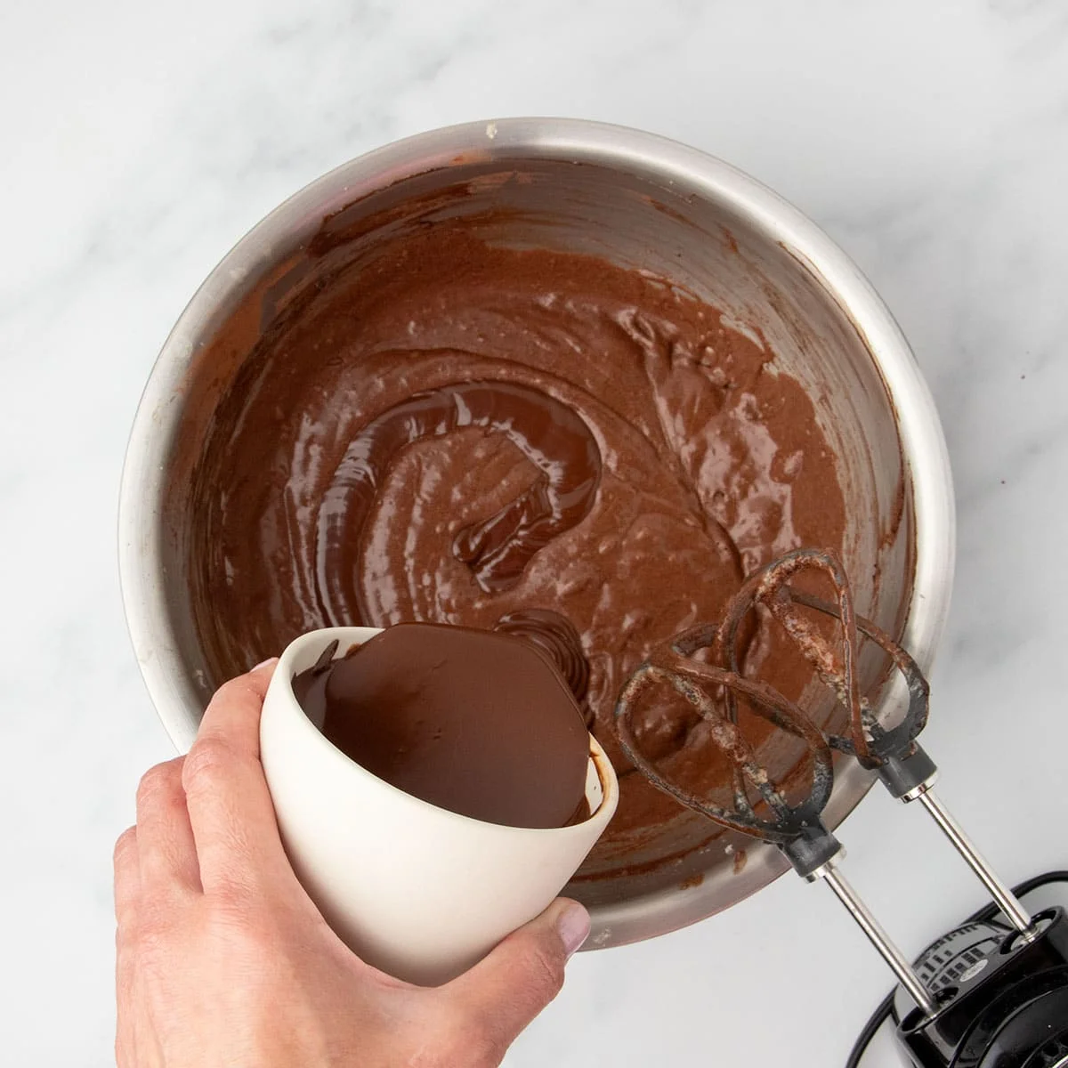 Melted chocolate being poured into the batter for even more richness