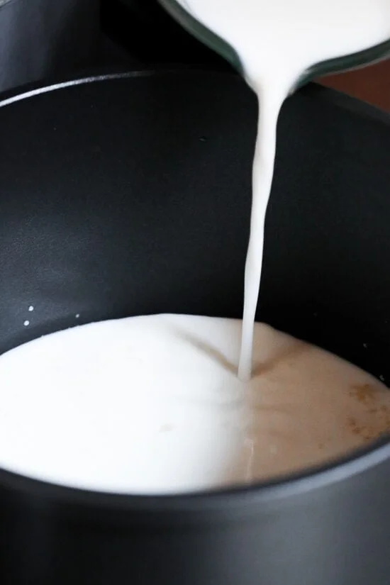 Milk being poured into a saucepot.