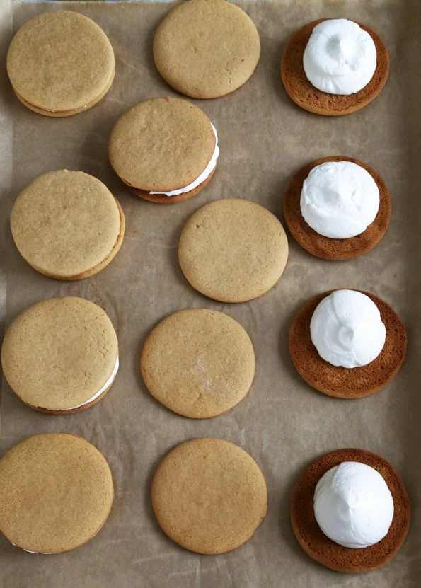 Moon pie cookies with marshmellow filling being put in.