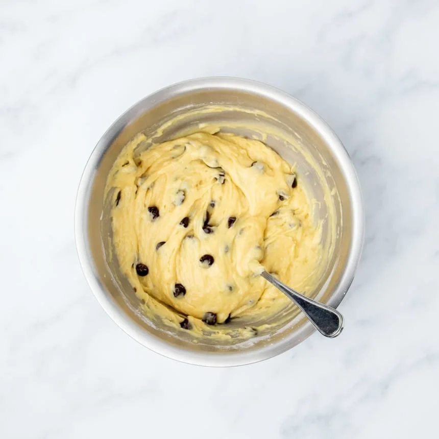 muffin batter in mixing bowl with dark brown chocolate chips mixed in