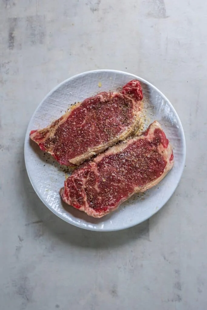 New York strip steak seasoned on a plate.