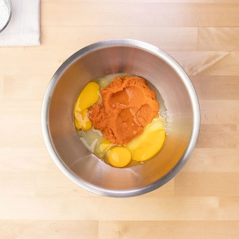 orange pumpkin puree, eggs, and white sugar in large metal mixing bowl