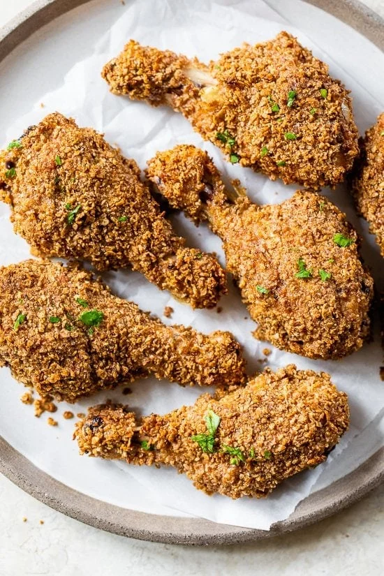 Oven fried chicken on parchment lined plate.