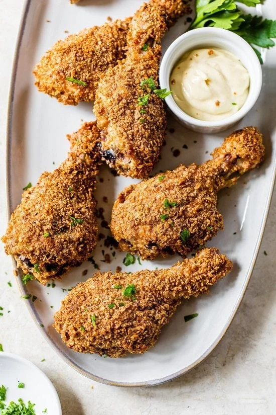 Oven fried chicken on platter with bowl of dipping sauce.