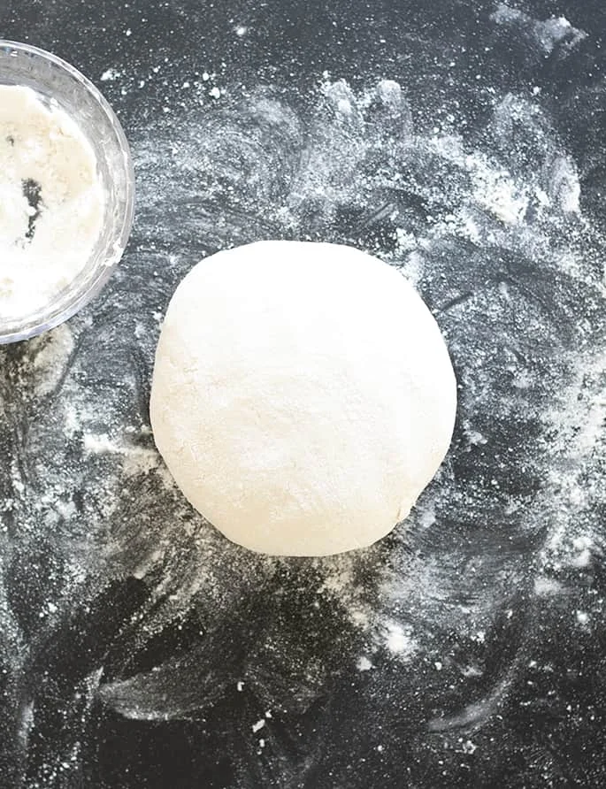 Overhead image of a ball of gluten free pizza dough and flour