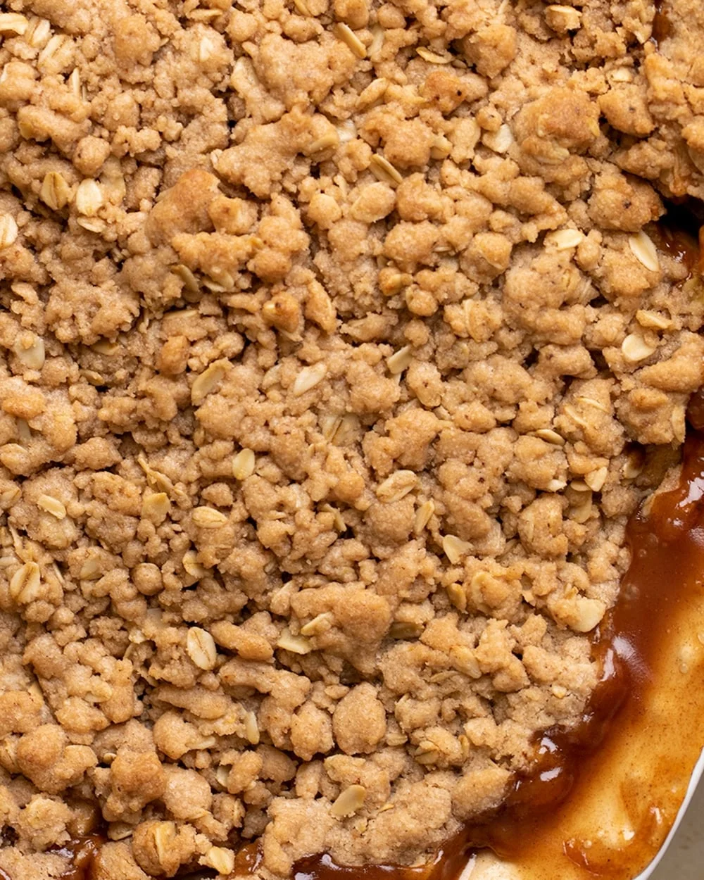 Overhead image of crisp topping with apple filling in a white casserole dish.