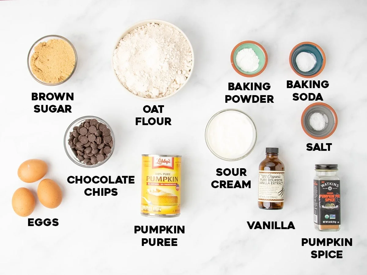 overhead image of ingredients for oat flour pumpkin muffins, including oat flour, pumpkin puree, sour cream, brown sugar, eggs and spices