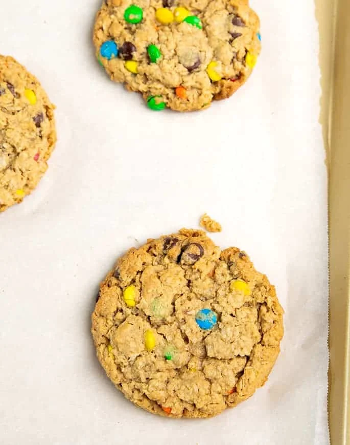 Overhead image of light brown round cookies baked on white paper-lined gold-colored tray