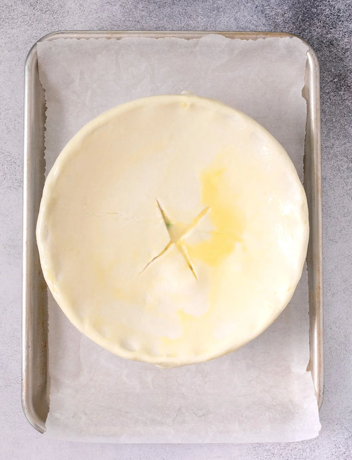 Overhead image of pie crust covering round casserole dish