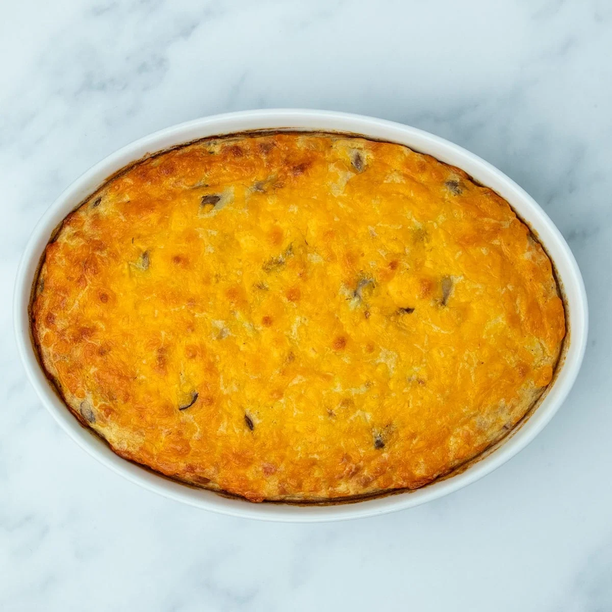 overhead image of white casserole dish with orange and browned melted cheese on top of cooked casserole
