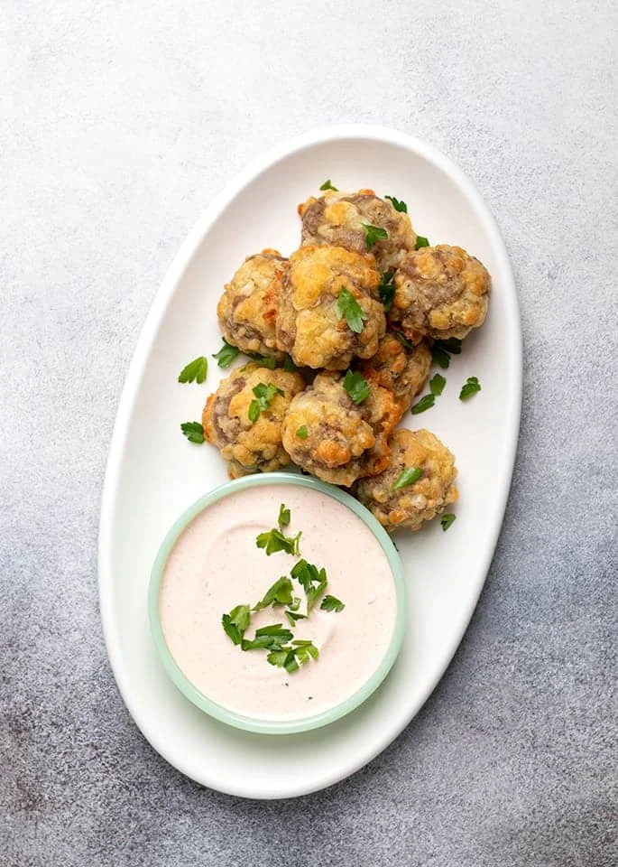 Overhead image of white oval platter with sausage balls and dipping sauce