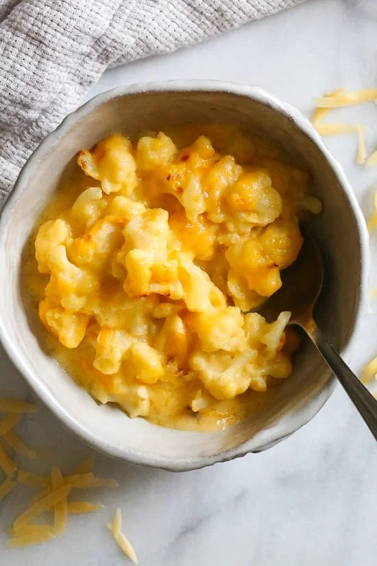 Overhead view of a bowl of cauliflower mac and cheese with a spoon.