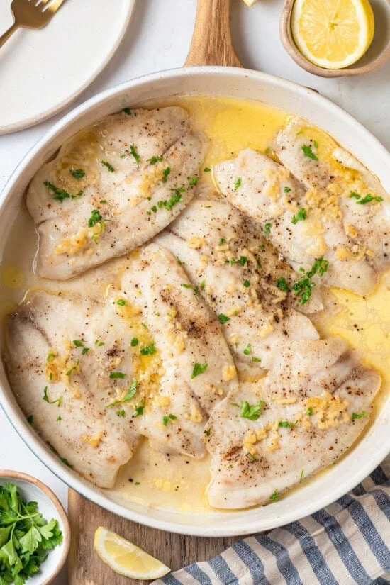 Overhead view of baked tilapia in skillet