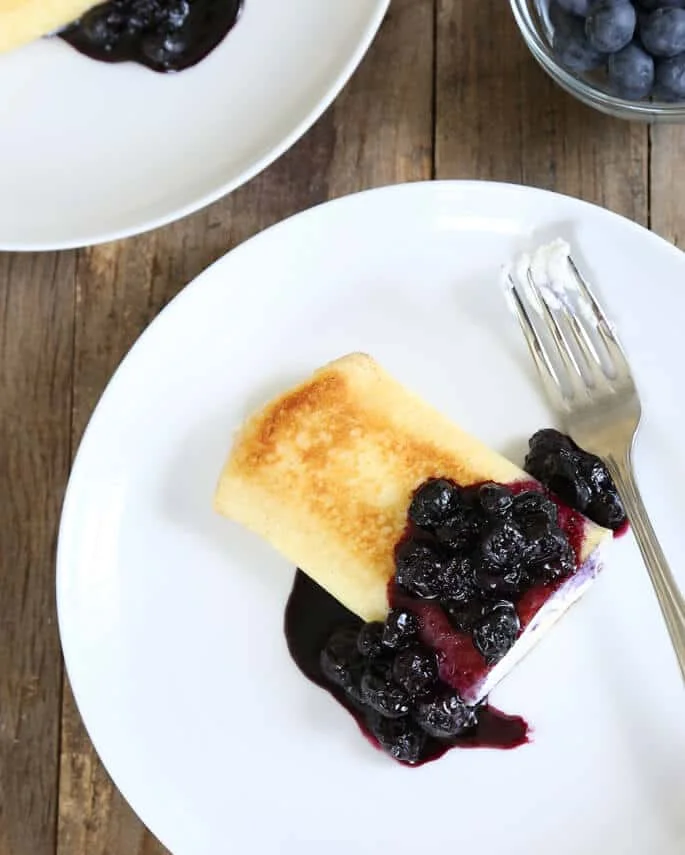 Overhead view of blintze on white plate with jam
