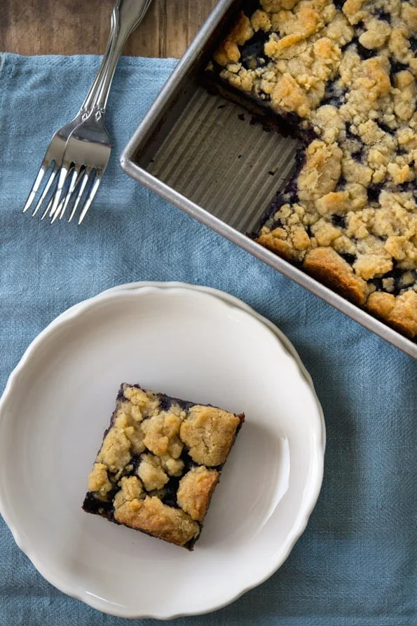 Overhead view of blueberry buckle on white plate.