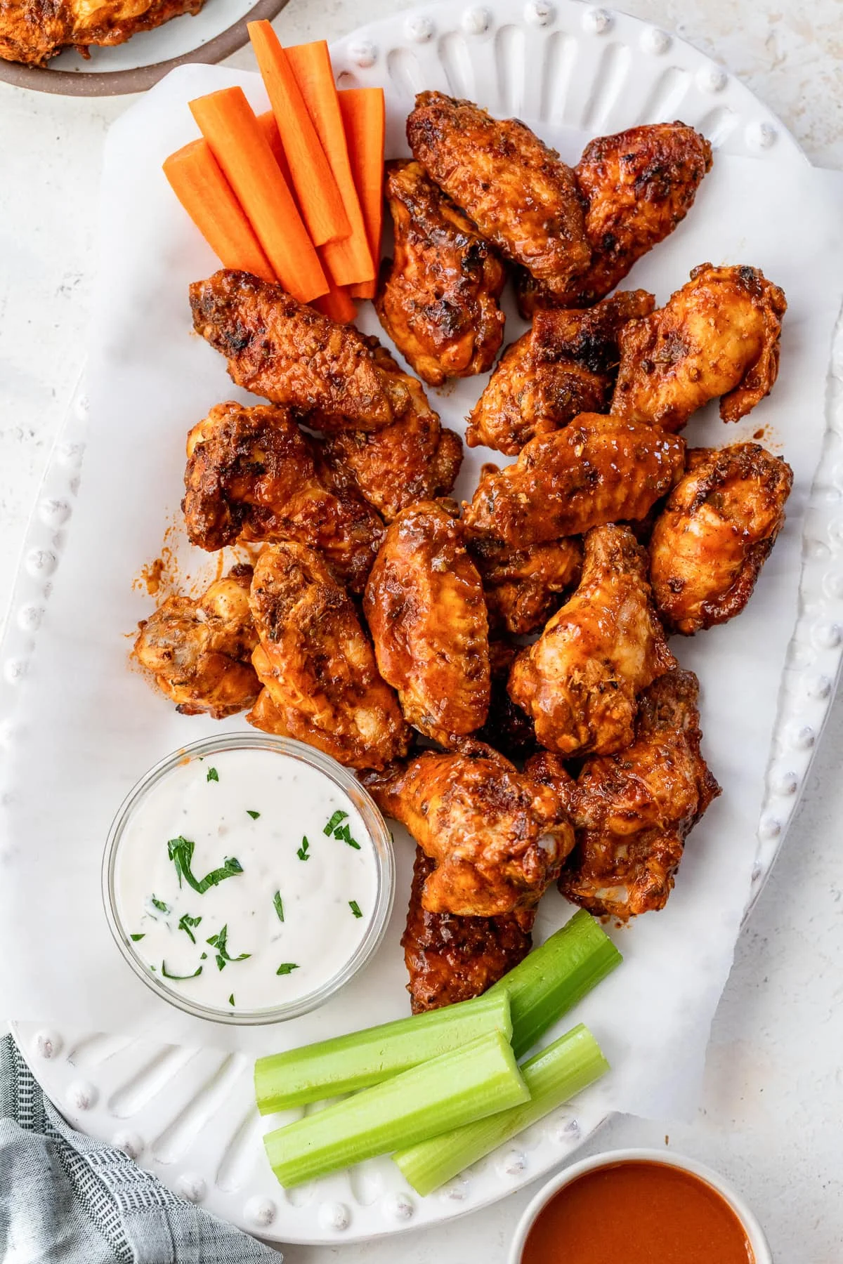 Overhead view of buffalo wings on a platter next to a bowl of blue cheese dressing and celery sticks.