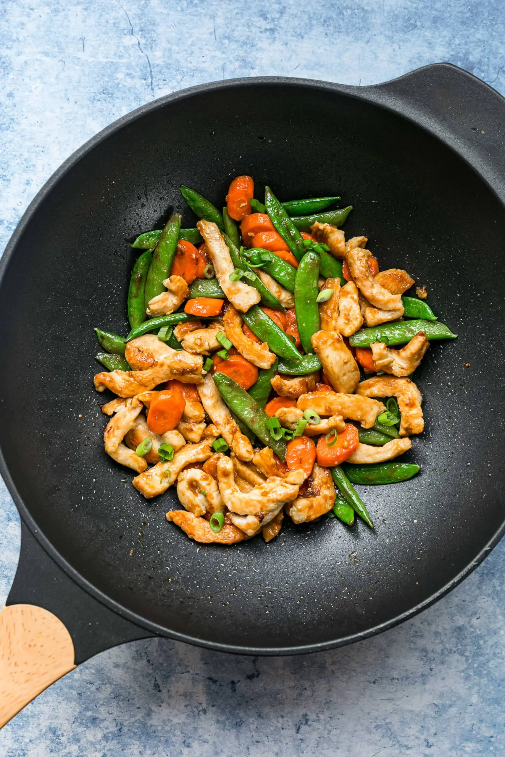 Overhead view of chicken and vegetable stir fry in a wok.