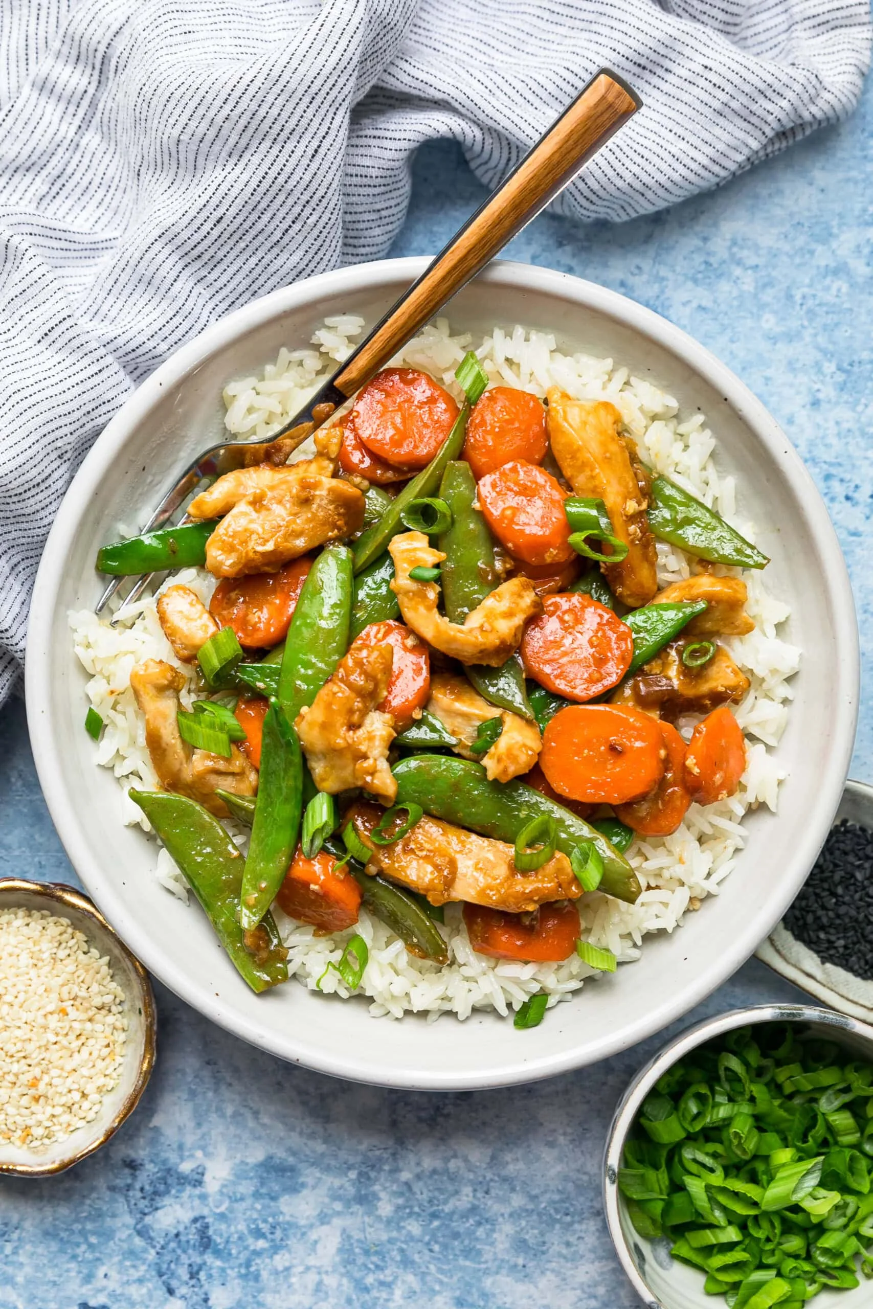 Overhead view of chicken and vegetable stir fry served over a bowl of rice.