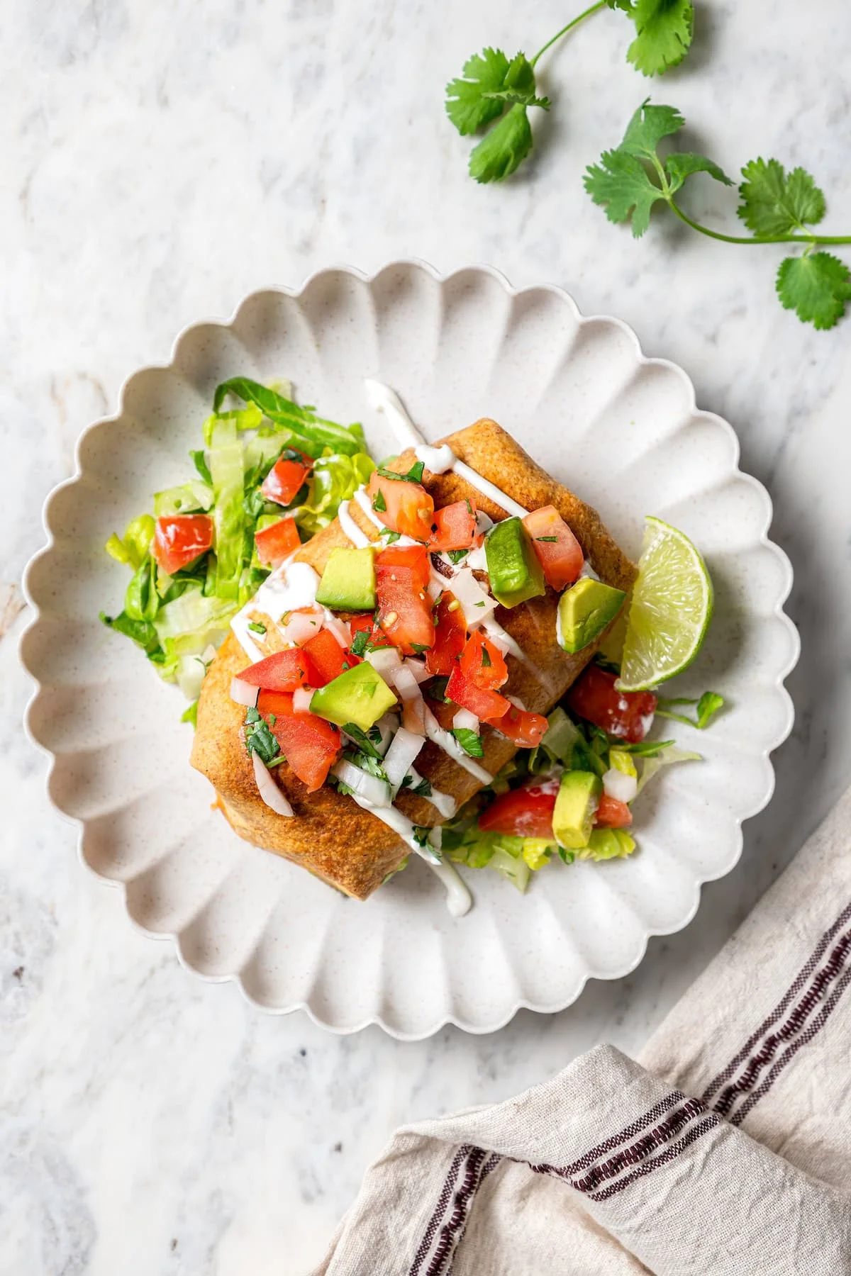 Overhead view of chicken chimichanga on plate with lettuce and toppings