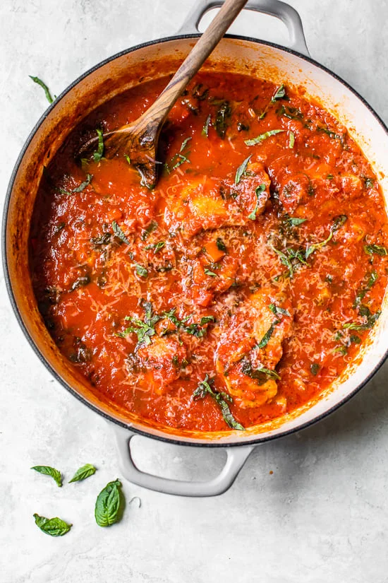 Overhead view of classic chicken cacciatore with peppers and tomatoes in a Dutch oven.