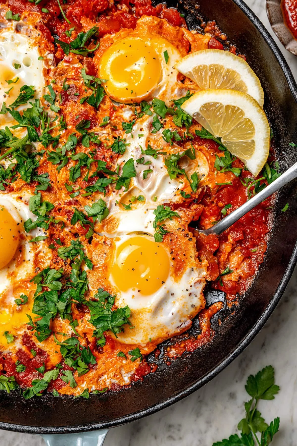 Overhead view of eggs in purgatory in skillet with spoon